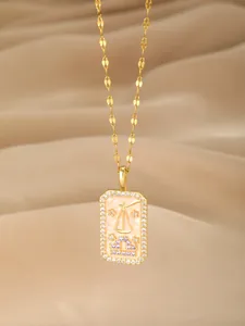 Makroaufnahme der goldenen Waage-Halskette mit rosa Emaille und Diamantakzenten
