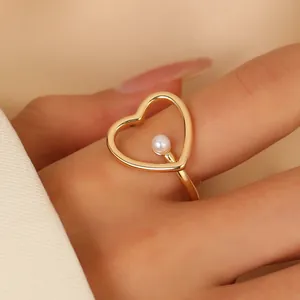 Adjustable hollow heart-shaped gold ring with center pearl on model's index finger