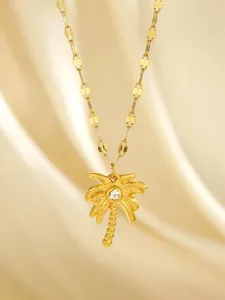 Detailed view of a gold-plated palm tree pendant with a sparkling zircon on a silk background