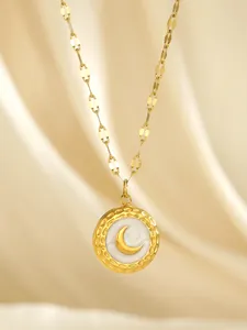 Detailed close-up of a gold-plated round pendant with crescent moon on satin background