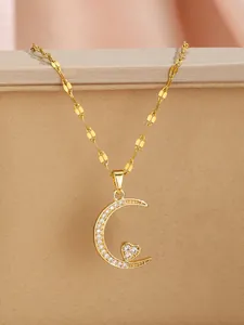 Detailed macro view of gold crescent moon and heart pendant with sparkling cubic zirconia