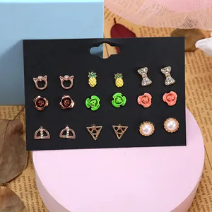 Detailansicht eines 9-Paar Ohrring-Sets mit Katzen-, Ananas- und Blumenmotiven auf Karte