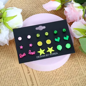 Detailansicht von 9 Paar bunten Dopamin-Stil Ohrsteckern auf einem rosa Display-Ständer