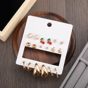 9-piece gold earring set with cherry, pearl and teardrop designs on a display card
