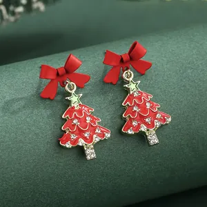 Christmas tree earrings with red bow and sparkling rhinestones on green display