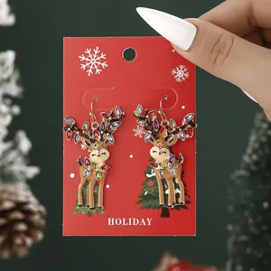 Christmas reindeer earrings with colorful rhinestones on festive holiday card display