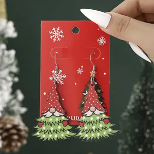 Christmas Gnome and Tree earrings on red snowflake card with cozy festive holiday background