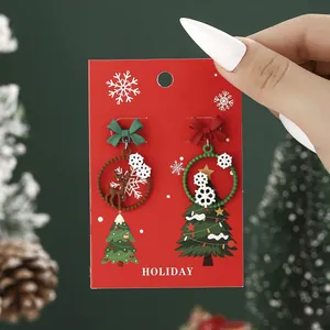 Christmas asymmetric reindeer and snowflake earrings with festive bows on holiday card
