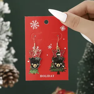 Festive Christmas reindeer and tree drop earrings on a red Holiday display card