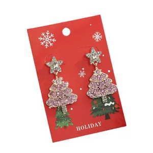 Kerstster en roze strassboom oorbellen gepresenteerd op een feestelijke rode kaart