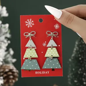 Christmas tree drop earrings with golden bows on a festive red holiday display card