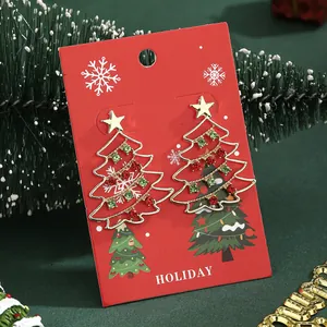 Detalle de pendientes de árbol de Navidad dorados con diamantes de colores en tarjeta