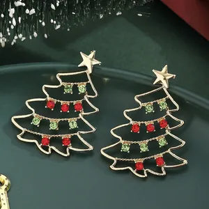Primer plano de pendientes de árbol de Navidad dorados con cristales en una bandeja