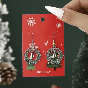 Christmas wreath earrings with green rhinestones and silver bells on a holiday card