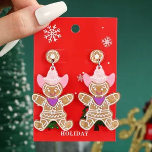 Close-up of pink cowboy hat gingerbread man earrings on festive red holiday card