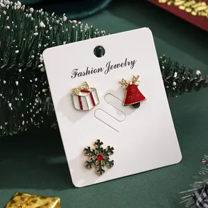 Three-piece set of Christmas brooches with bell, snowflake, and gift box on a white card