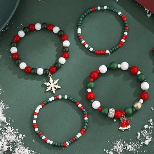 Set of four Christmas beaded bracelets with Santa and snowflake charms on green background