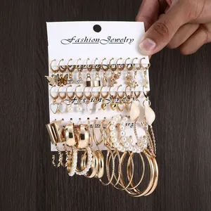 Golden earring set featuring gold hoops, faux pearls, and charms on white display card