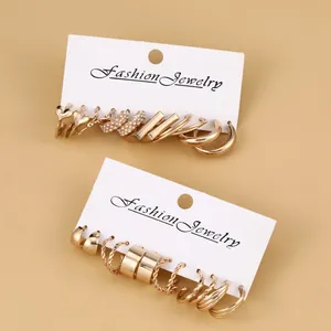 Close-up of gold hoop earrings set with pearls and twisted textures on display card