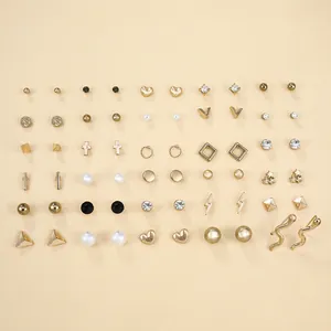 Dettaglio di un set da 30 paia di orecchini dorati con perle e forme geometriche