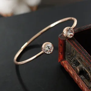 Minimalistischer Roségold-Armreif mit zwei Zirkonia-Steinen auf dunklem Holzdekor