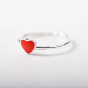 Macro shot of minimalist silver ring with a polished red heart detail on white background