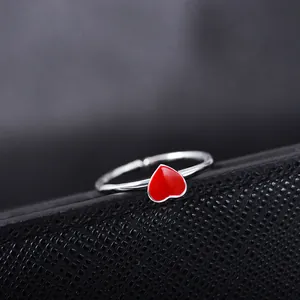 Detail of silver adjustable open ring featuring a vibrant red heart enamel element