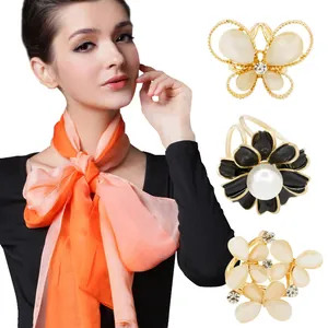 Close-up of rhinestone flower scarf clips and orange gradient silk scarf detail