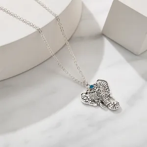 Detail of silver hollow elephant pendant with blue stone and vintage chain necklace
