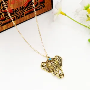 Vintage gold elephant pendant necklace with blue gemstone detail on a white surface