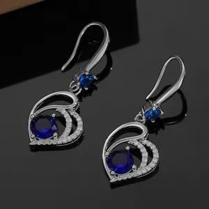 Macro detail of heart-shaped blue zircon earrings with silver frame and pavé diamonds