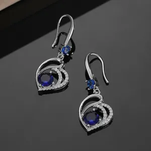Detail of silver heart-shaped drop earrings with dark blue sapphire-like stones and crystals