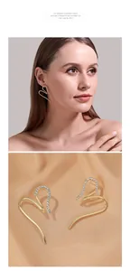 Close-up of golden heart tassel earrings with sparkling rhinestones on champagne silk
