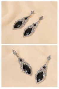 Close-up of geometric rhombus earrings with black gemstones and sparkling crystals