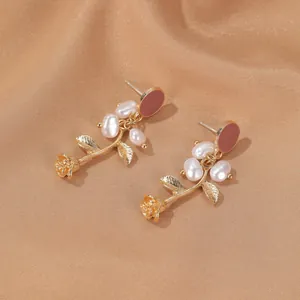 Elegant gold rose earrings with white baroque pearls on a luxurious silk background