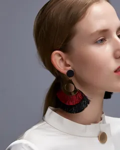 Close-up of Bohemian hollow metal earrings with red and black layered tassels on a model