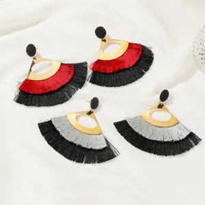 Macro shot of tiered bohemian fringe earrings with gold fan-shaped metal accents