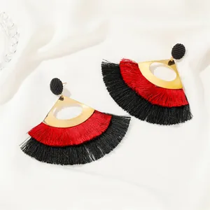Detail of bohemian fan-shaped earrings with red and black silk fringe tassels