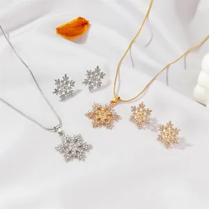 Elegante Schmucksets mit Schneeflocken in Gold und Silber mit Kristallen auf weißer Seide