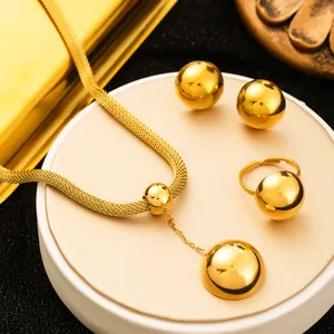 Close-up of polished gold-plated stainless steel jewelry set with spherical studs and necklace