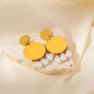 Close-up of gold geometric earrings with hanging pearls on a luxury silk background