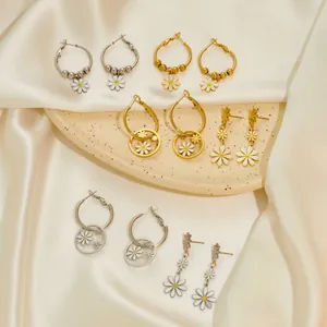 Gänseblümchen Ohrringe Set in Gold und Silber auf elegantem Seidenhintergrund