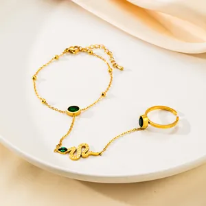 Elegante set bracciale anello a serpente dorato con pietre verdi su tessuto di seta