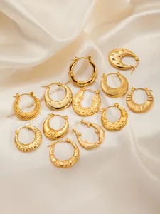 Macro shot of gold stainless steel hoop earrings with textured vintage patterns on silk
