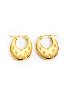 Detail of gold-plated moon-shaped hoop earrings with textured oval embossed patterns