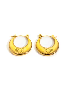 Detailed macro view of golden crescent earrings featuring sunburst engravings and polished finish