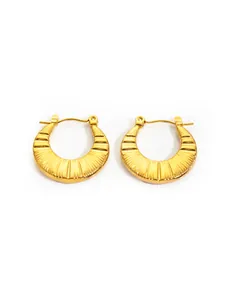 Macro detail of gold-plated hoop earrings featuring a unique radial textured finish