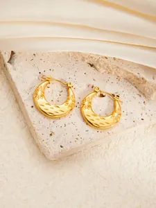 Detailed macro view of gold-plated chunky hoop earrings with engraved starburst texture