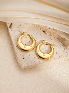 Detailed macro view of 18K gold-plated star engraved thick hoop earrings on satin