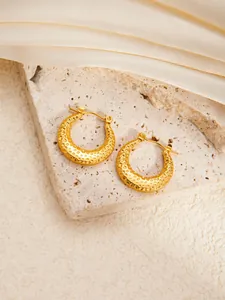Detailed macro view of gold-plated stainless steel hoop earrings with hammered texture